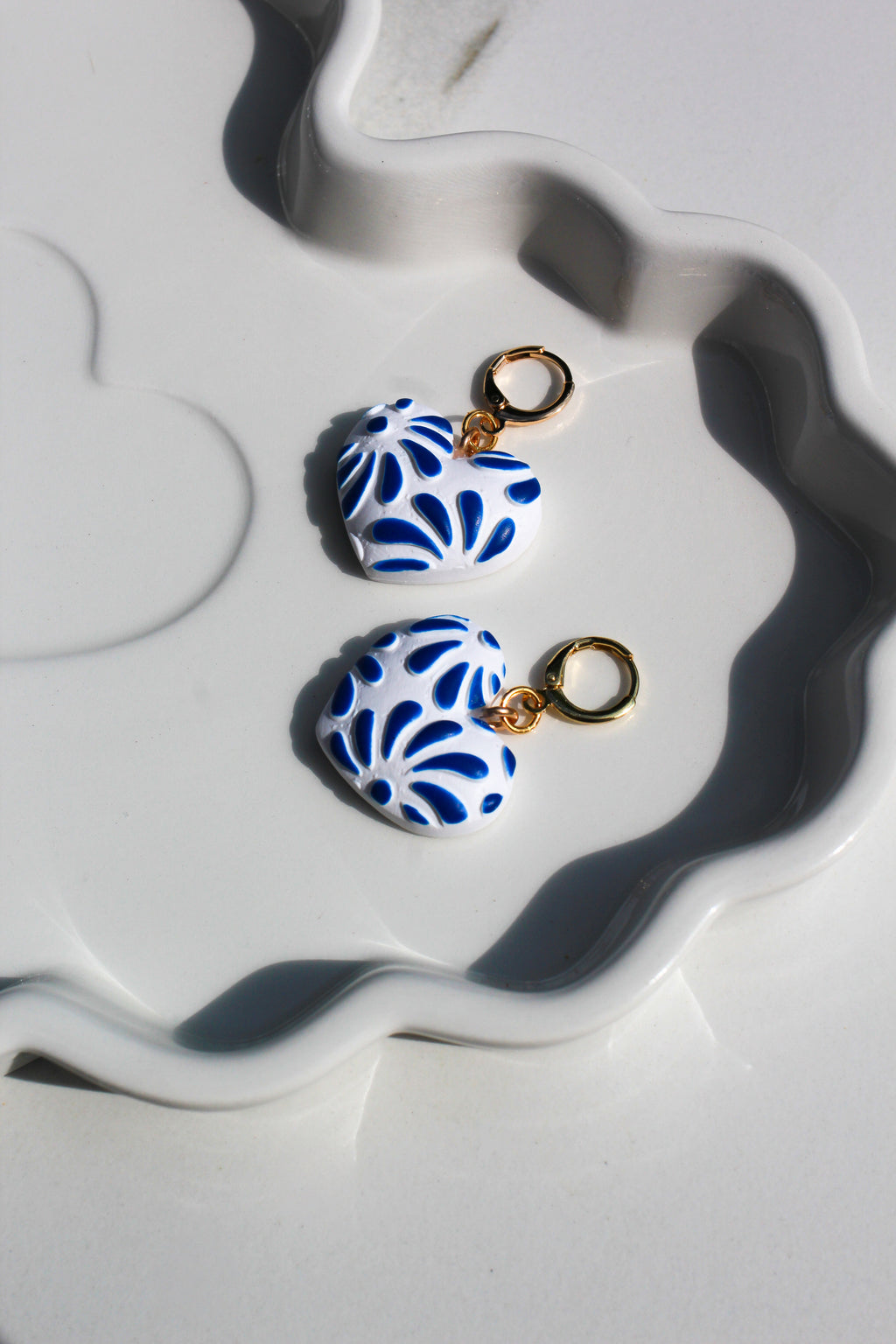 Pair of blue and white patterned earrings on a white dish