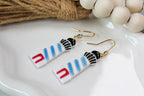 Pair of lighthouse earrings with colorful design on a white dish