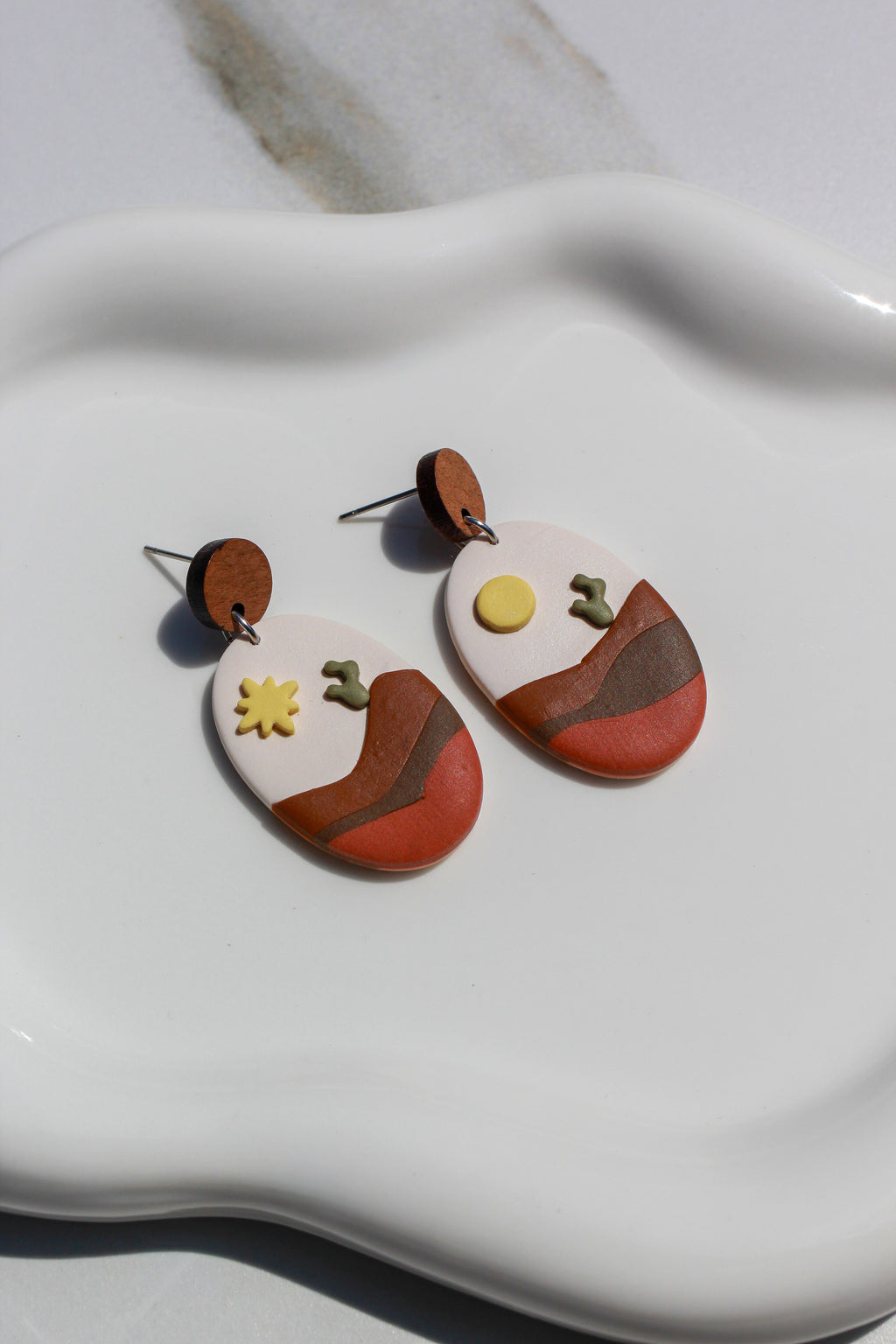 Dessert style earrings on a white dish