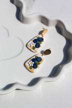 Decorative earrings with floral designs on a white surface