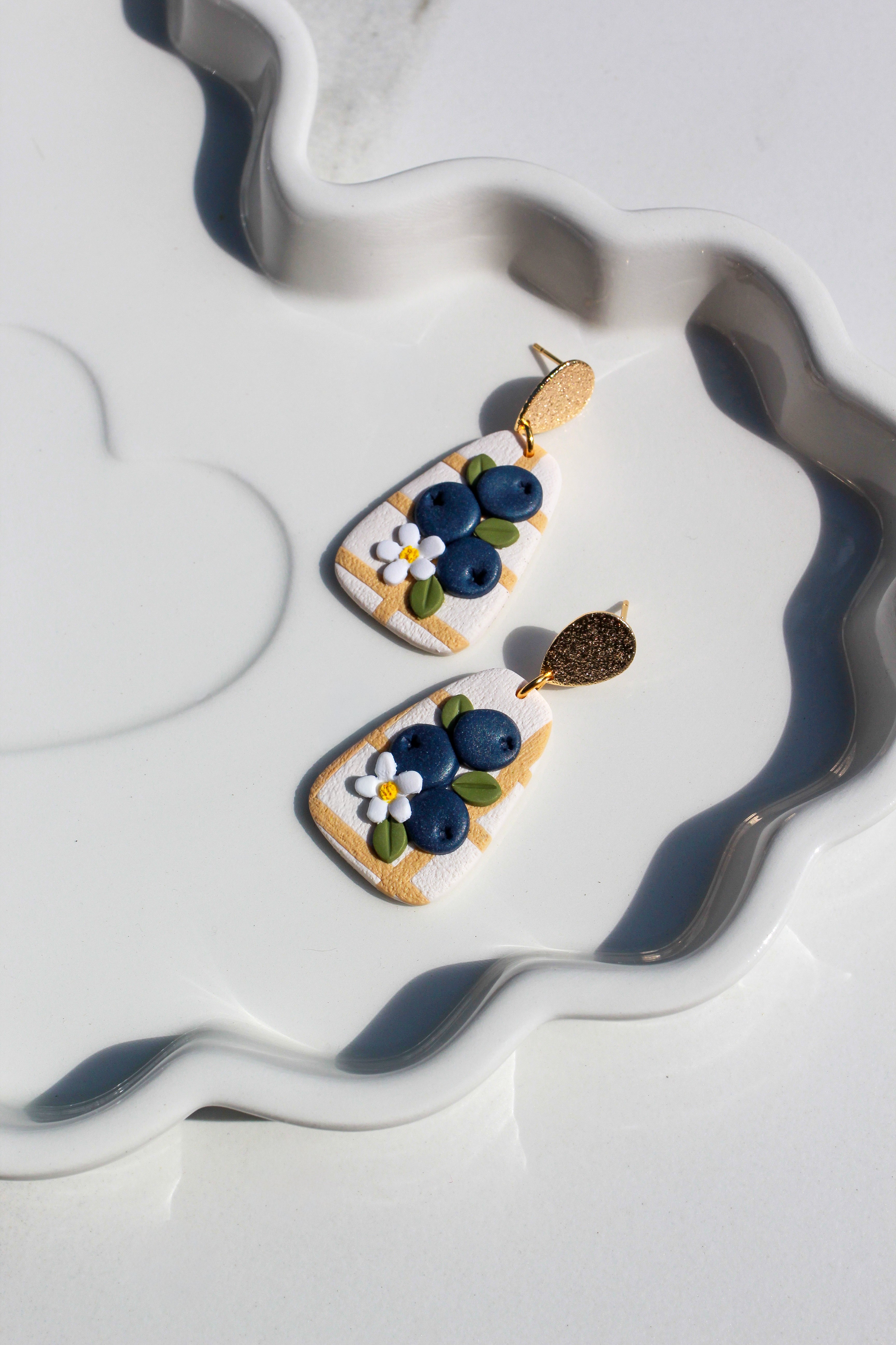 Decorative earrings with floral designs on a white surface