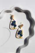 Pair of earrings with blueberry design on a white dish