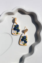 Pair of earrings with blueberry design on a white dish