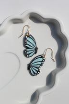 Butterfly-shaped earrings on a white dish