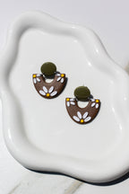 Pair of floral earrings on a white dish with a light background