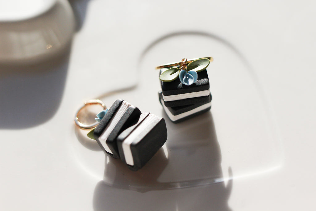 Pair of black and white squared book earrings with green and blue accents on a light surface.