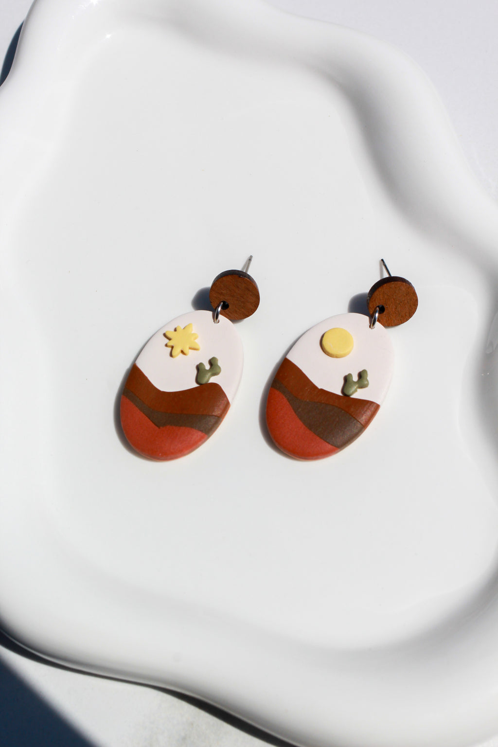 Pair of earrings with abstract design on a white fabric background
