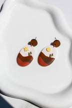 Pair of earrings with abstract design on a white fabric background