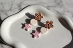 Pair of earrings with beachy floral and star designs on a marble surface