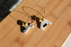 Pair of cow head hoop earrings on a wooden surface