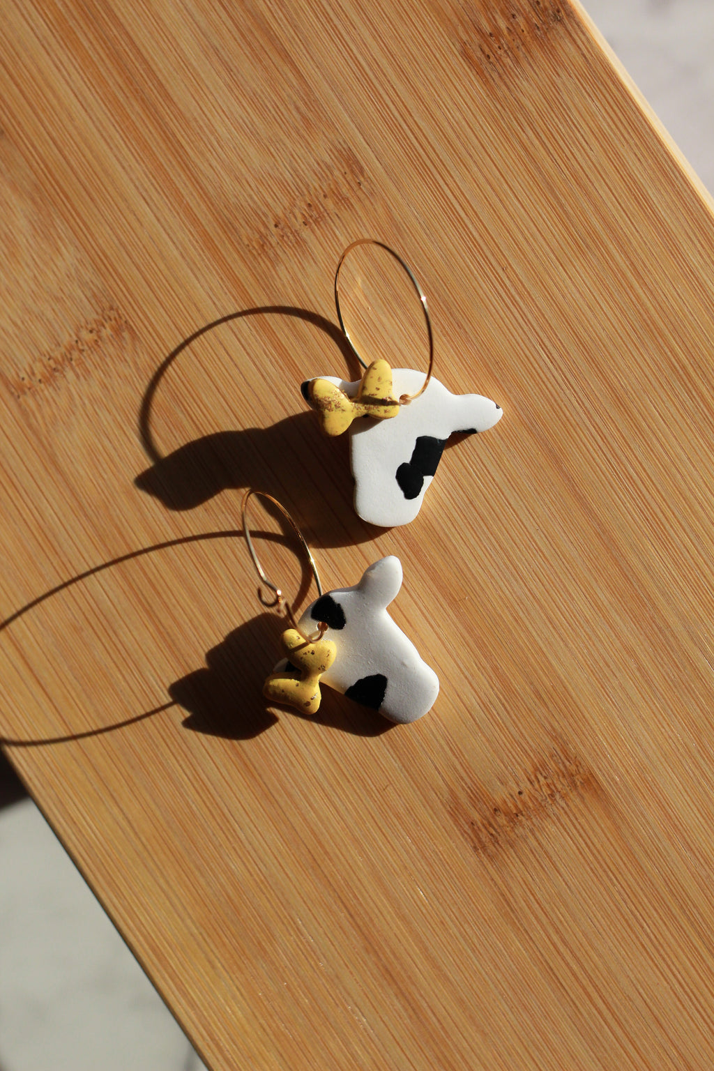 Cow-shaped hoop earrings on a wooden surface