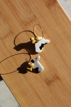 Cow-shaped hoop earrings on a wooden surface