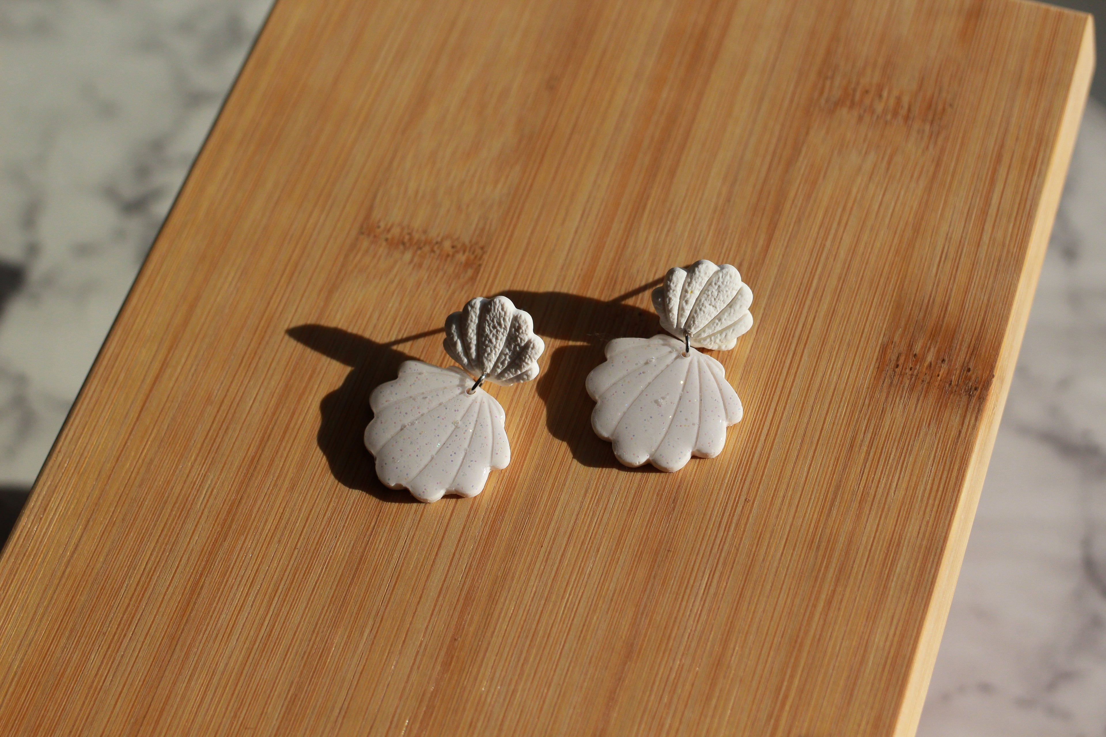 Shell-shaped earrings on a wooden surface