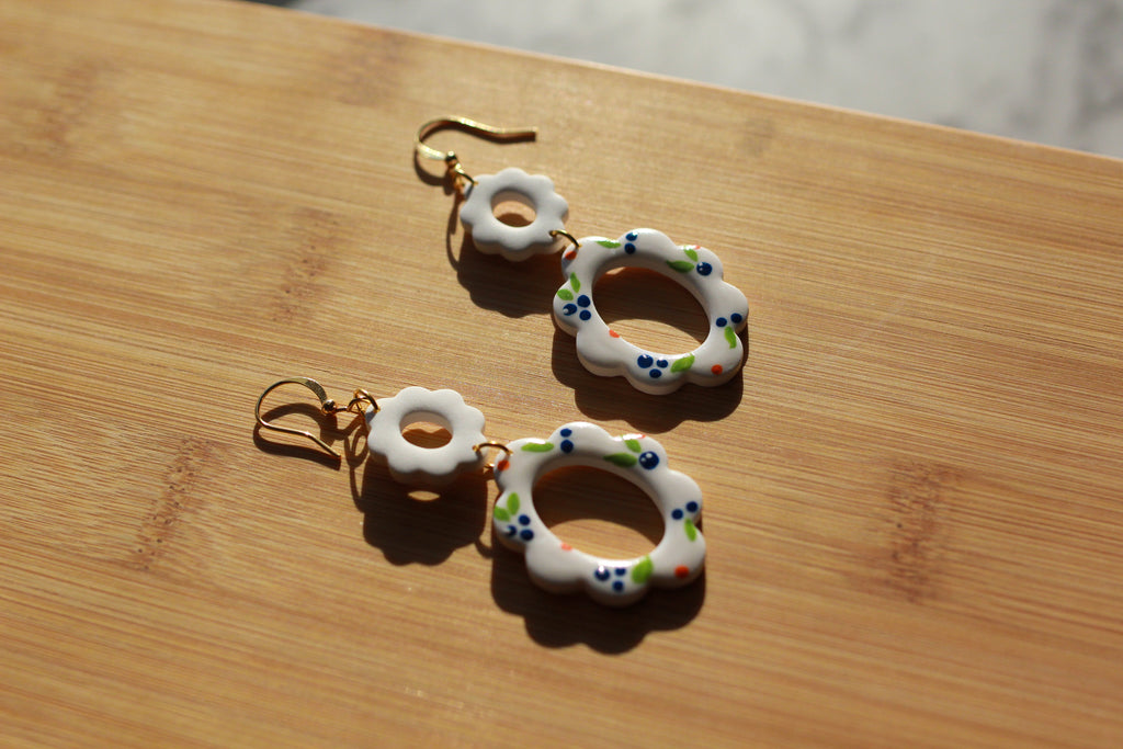 Pair of earrings with floral designs on a wooden surface
