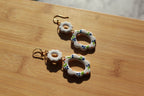 Pair of earrings with floral designs on a wooden surface