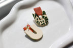 Pair of colorful earrings on a white dish