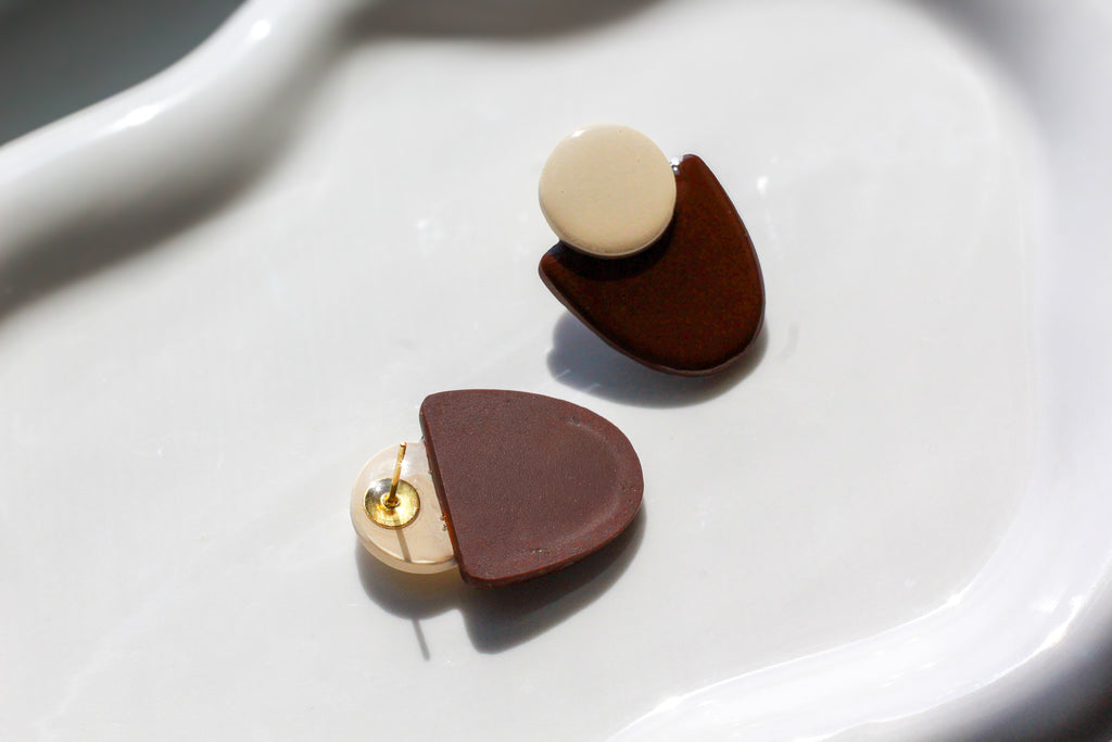 Pair of earrings with brown and beige half-circle designs on a white surface