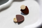 Pair of earrings with brown and beige half-circle designs on a white surface