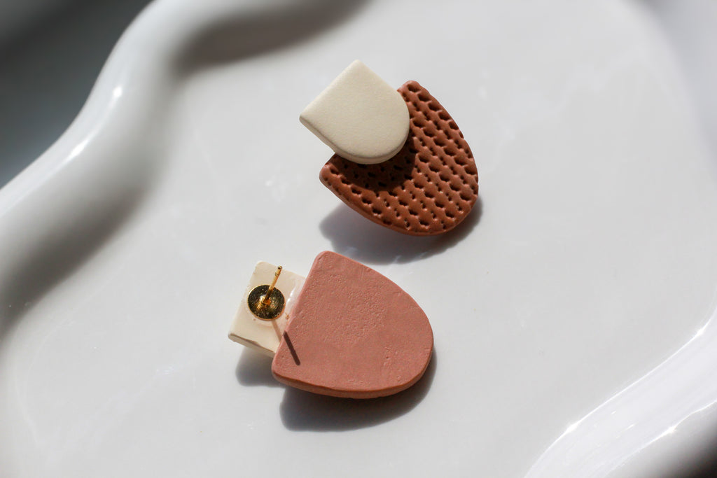 Pair of earrings with geometric designs on a white surface