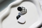 Black and white geometric earrings on a white dish