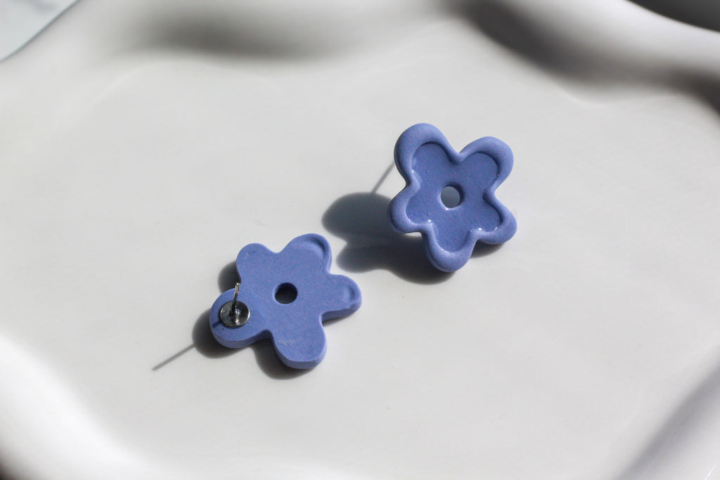 Pair of blue flower-shaped earrings on a light gray background