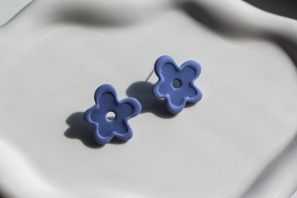 Pair of blue flower-shaped earrings on a light gray background