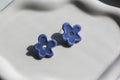 Pair of blue flower-shaped earrings on a light gray background