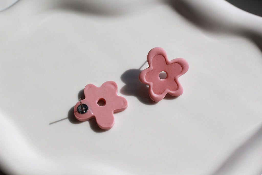 Pink flower-shaped earrings on a light background
