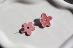Pink flower-shaped earrings on a light background