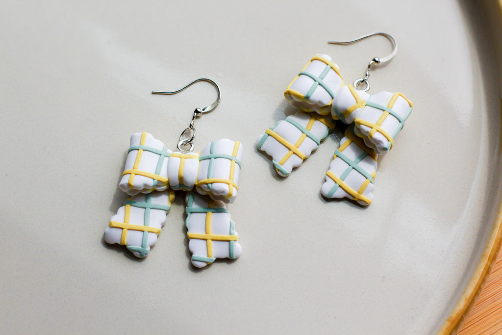 Bow-shaped earrings with plaid pattern on a light gray surface