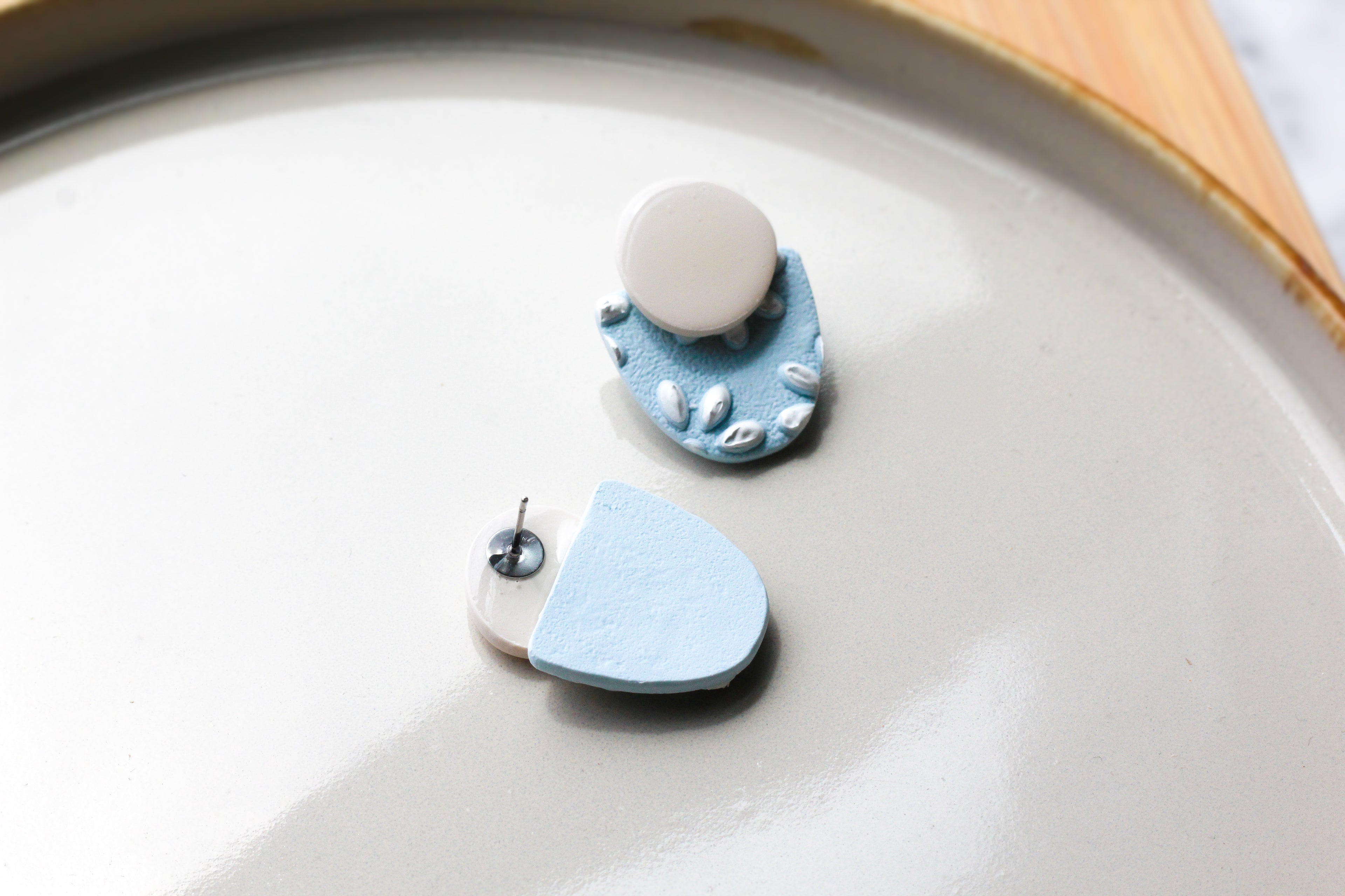 Pair of blue and white earrings on a ceramic plate