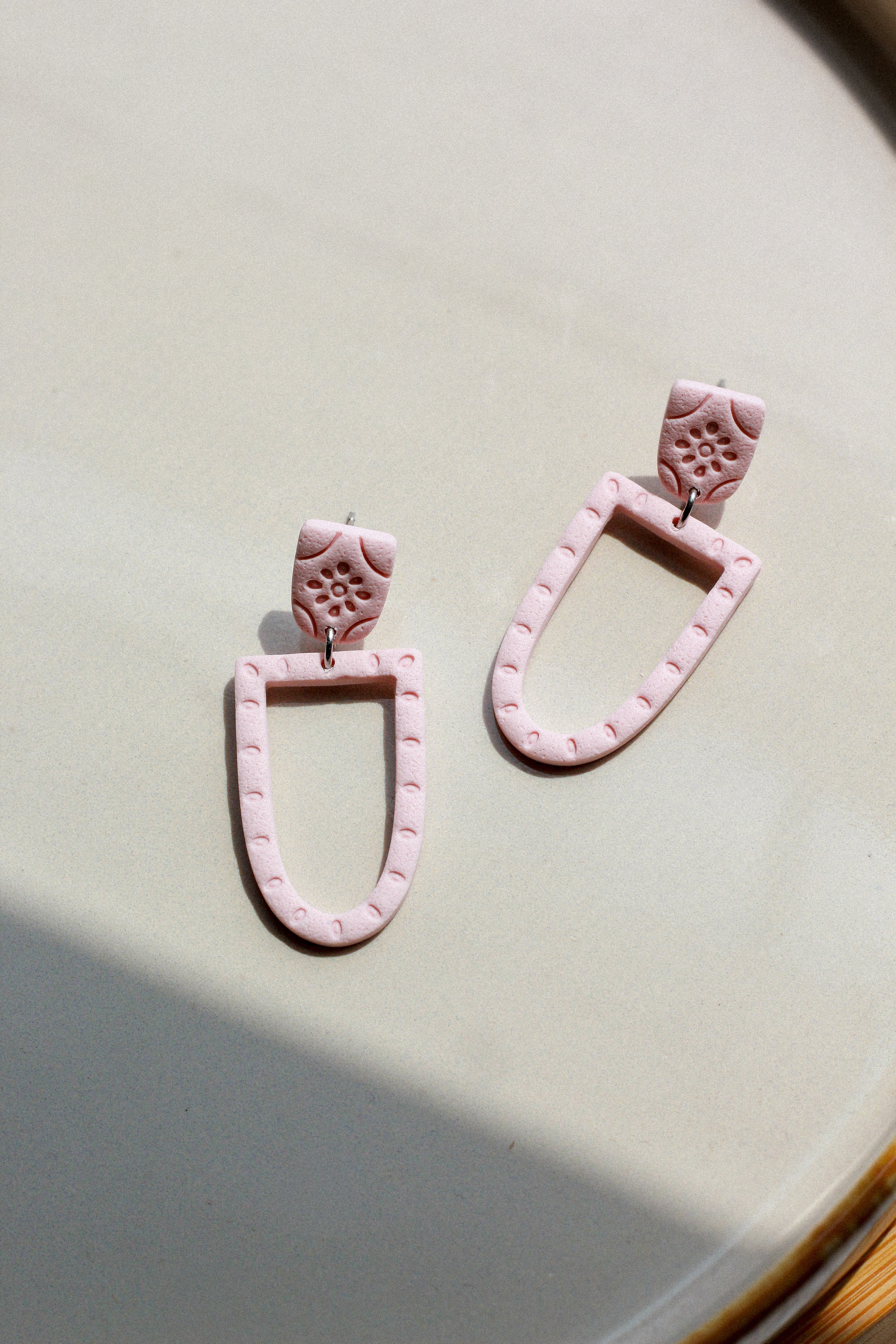 Pink earrings on a light beige surface
