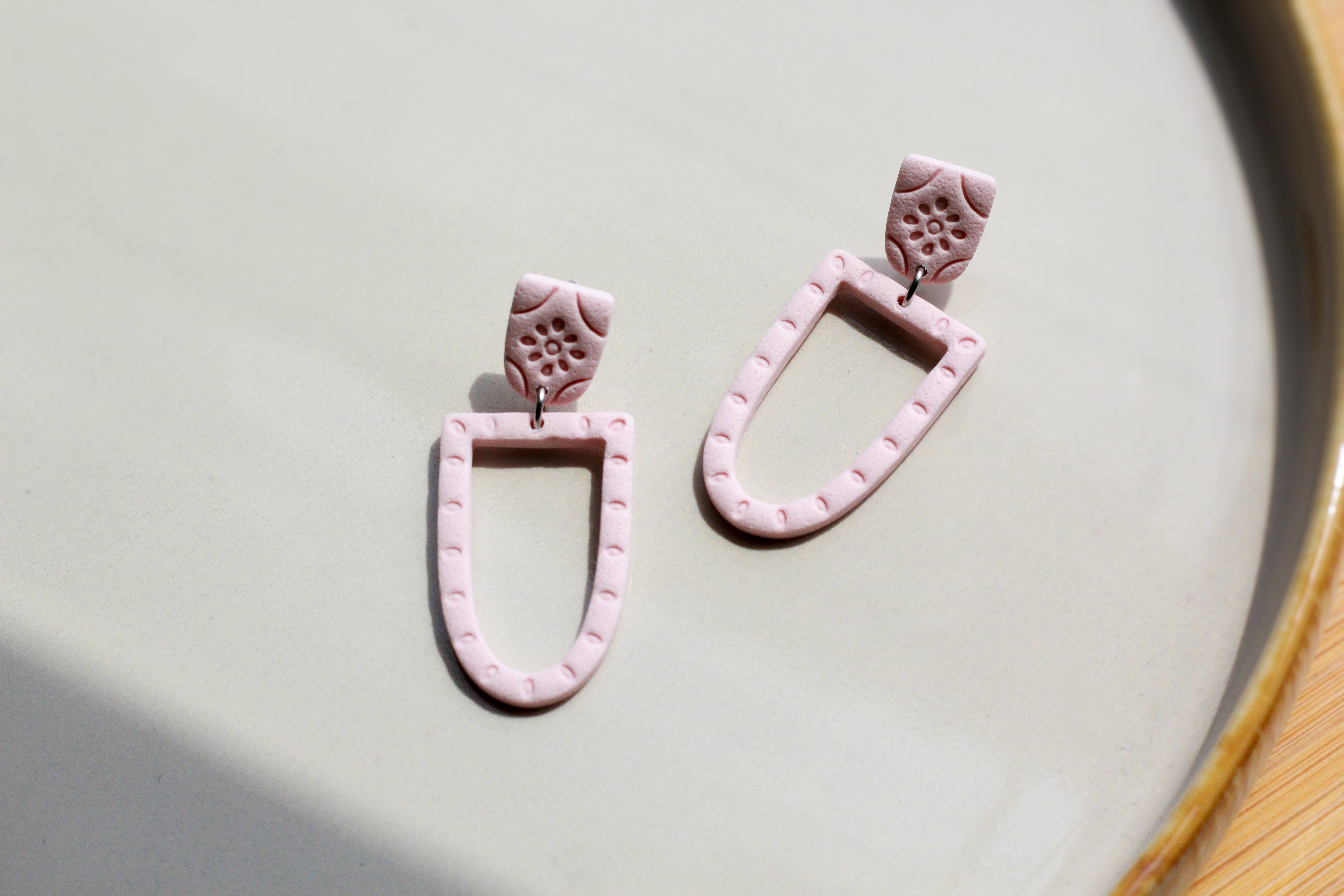 Pink ceramic earrings on a light gray surface