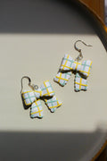 Pair of checkered earring bows on a light background