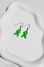 Green ribbon earrings on a white dish