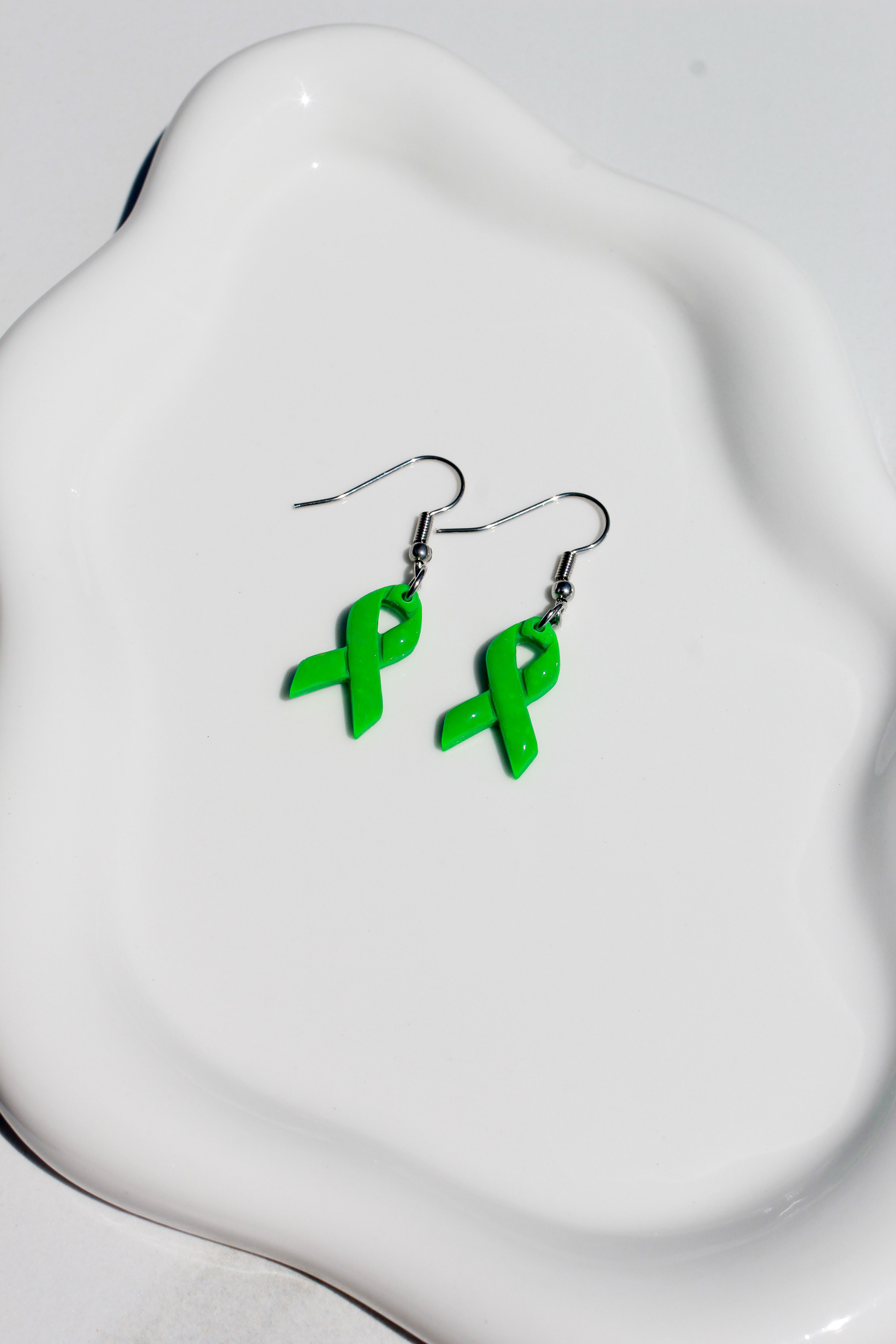 Green ribbon earrings on a white dish
