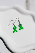 Green ribbon earrings on a white glass background
