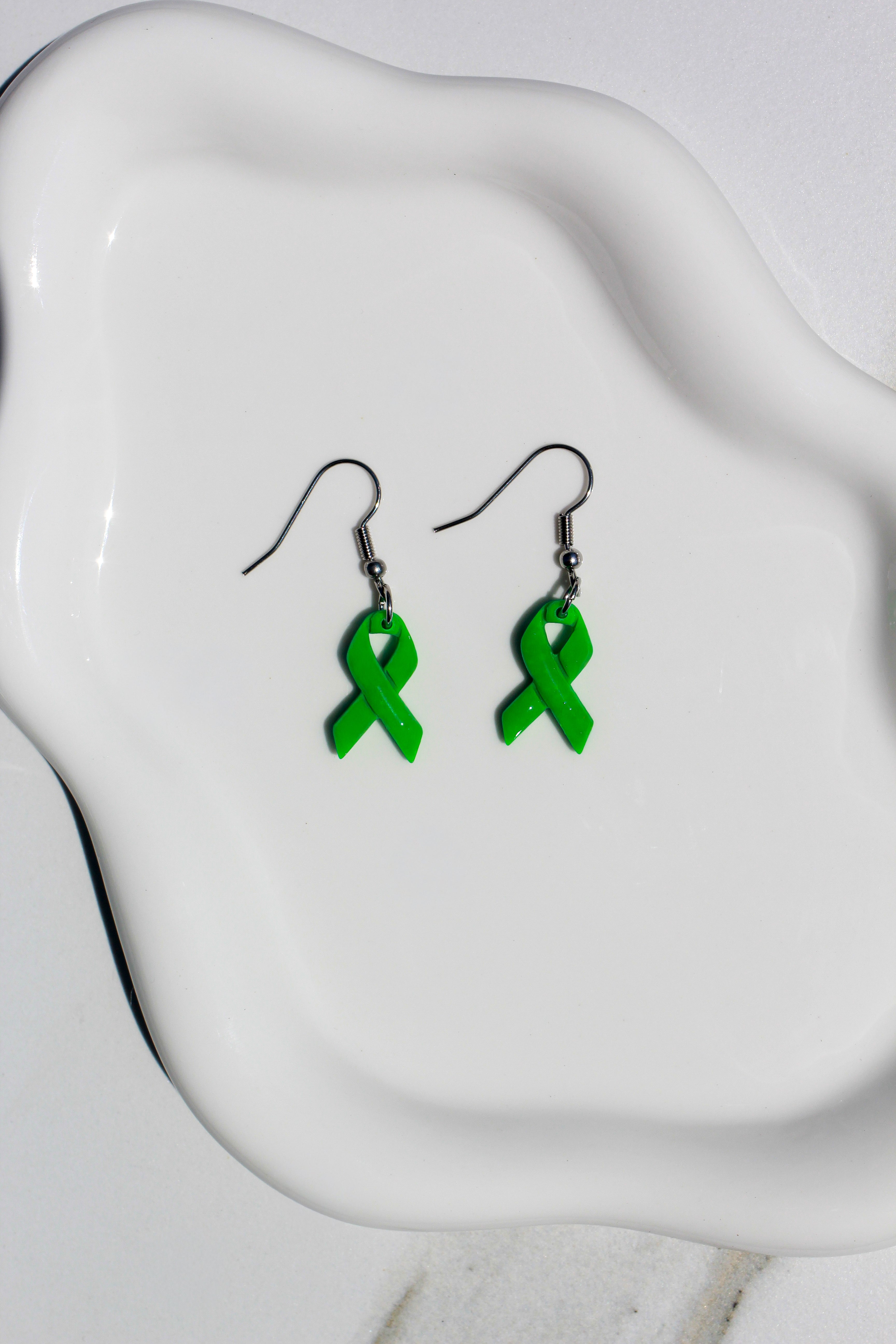Green ribbon earrings on a white dish