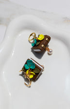 Pair of book earrings with floral designs on a white dish