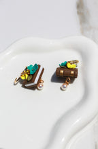 Pair of book earrings with florals on a white surface