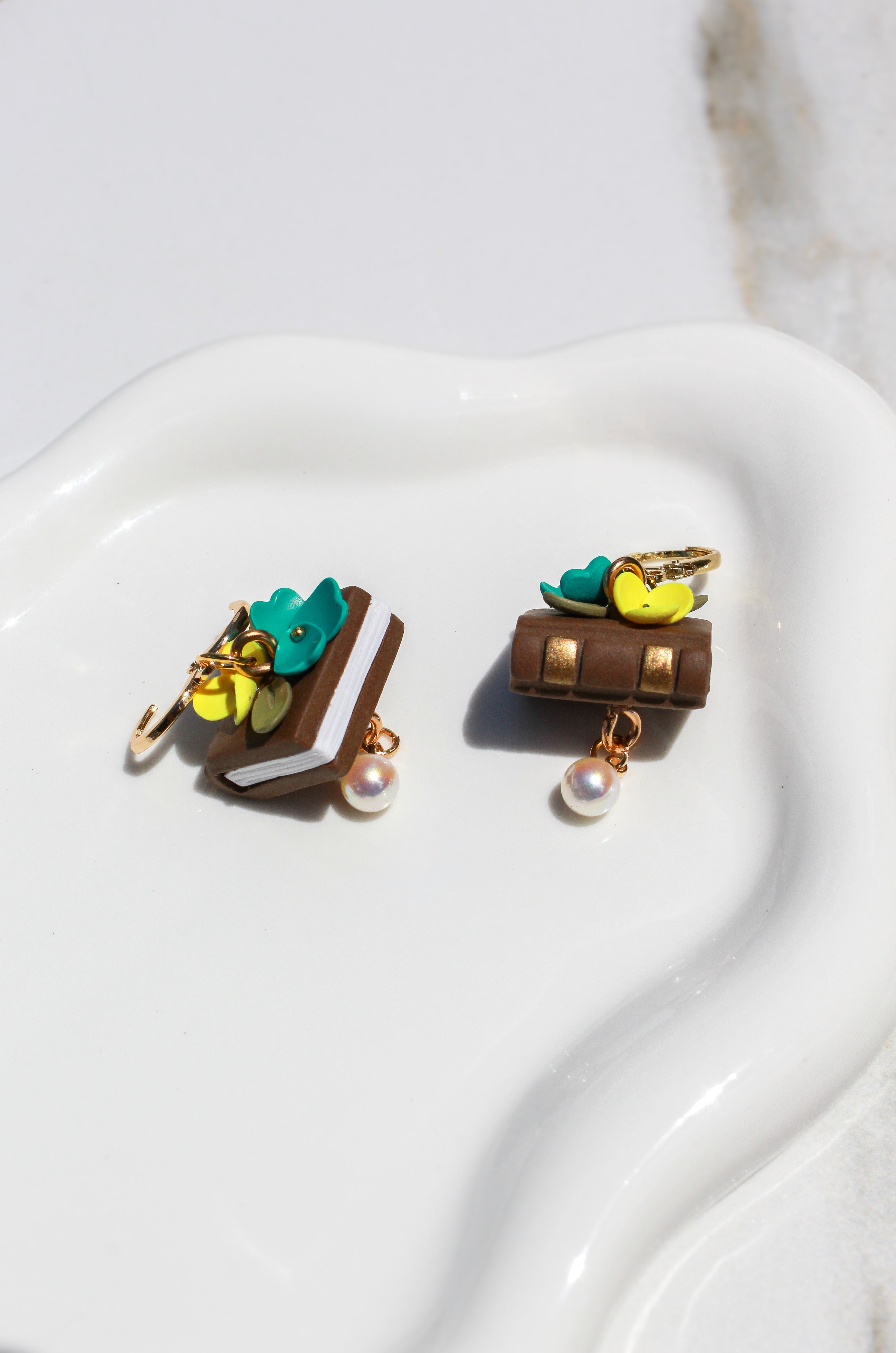 Pair of book earrings with florals on a white surface
