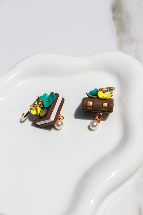 Pair of book earrings with florals on a white surface