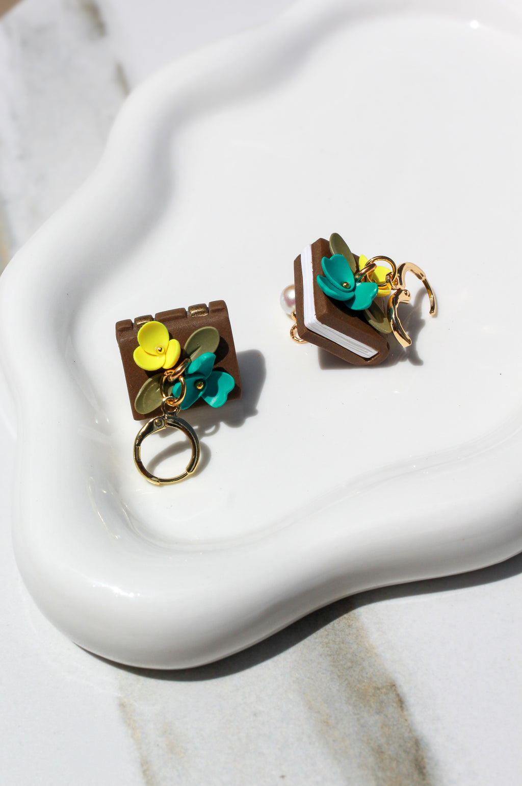 Pair of book earrings with floral design on a white surface