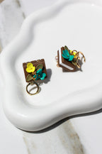 Pair of book earrings with floral design on a white surface