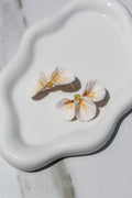 Floral earrings on a white ceramic dish with a marble background
