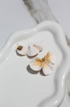 Floral earrings on a white ceramic dish with a marble background