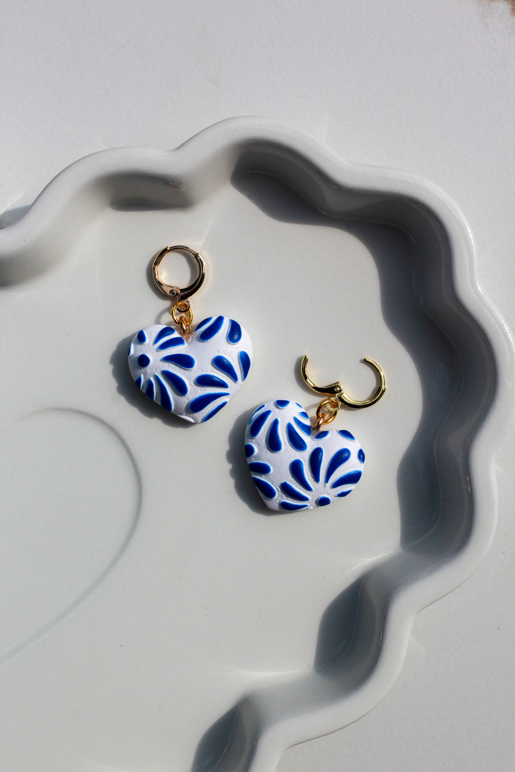 Pair of blue and white patterned earrings on a decorative white dish.