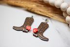 Cowboy boot earrings with coral flowers and pearl accents on a white surface.