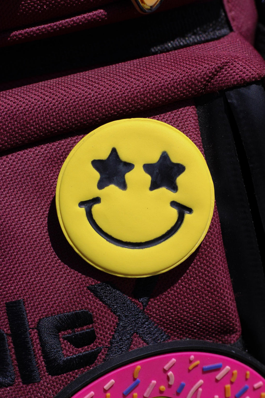 Close-up of a smiley face pin on a red bag