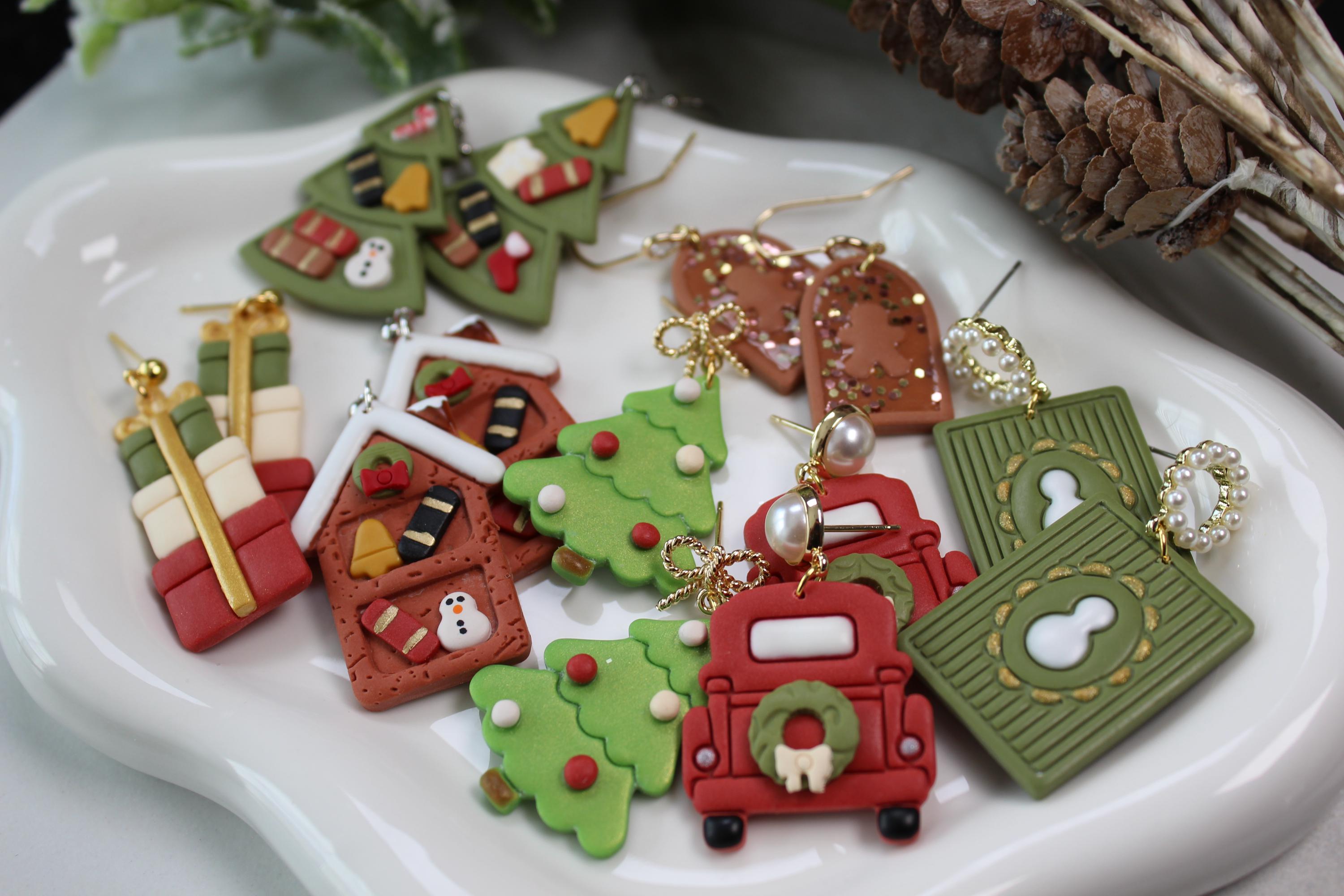 Colorful Christmas-themed earrings on a white dish with decorative elements.